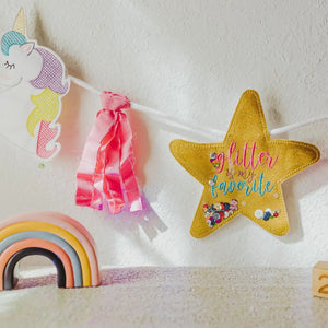 Rainbows & Unicorns Birthday Banner fabric tassel and golden glitter star hanging on the wall with a rainbow figurine Tiny Owls Gift Co