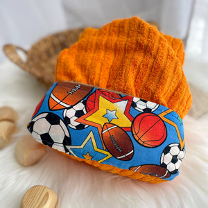 Orange hooded towel with sports-themed fabric on a white surface