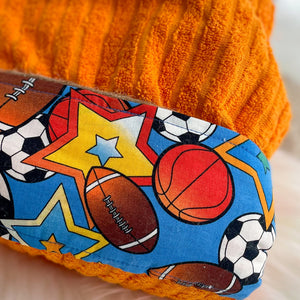 Colorful sports-themed towel with football, soccer ball, and basketball on fabric trim