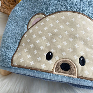 Close-up of a blue towel with a teddy bear face design on a white surface