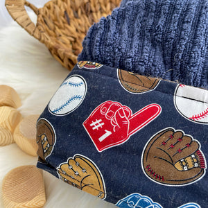 Close up Navy blue hooded towel featuring fabric with ball gloves baseballs foam fingers