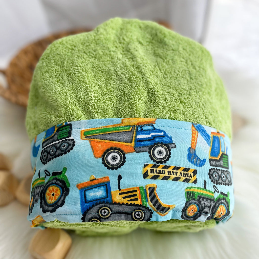 Lime Green Hooded towel folded with a pale blue fabric featuring tractors dump trucks loader and backhoes