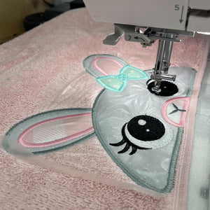 Embroidery design of a bunny face on fabric with a sewing machine.