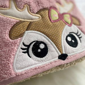 Close-up of a plush toy with a deer face design on a pink background
