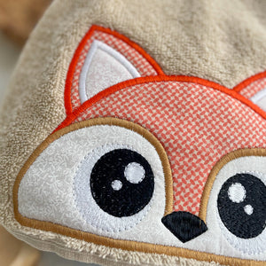 close up of a fox face appliqued on a tan hood of a towel