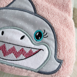 Close-up of a shark kids hooded towel with a pink background