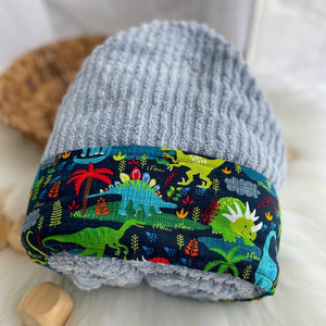 Light blue hooded towel with colorful dinosaur pattern on a white surface