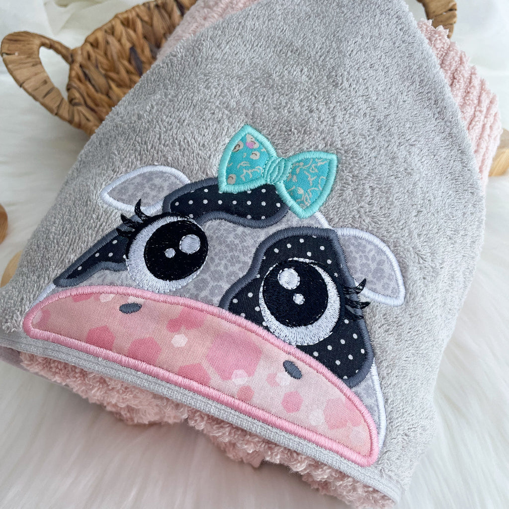Grey towel hood with a black and white cow face with teal bow
