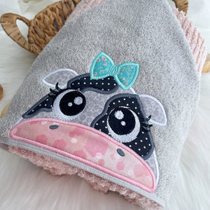 Grey towel hood with a black and white cow face with teal bow