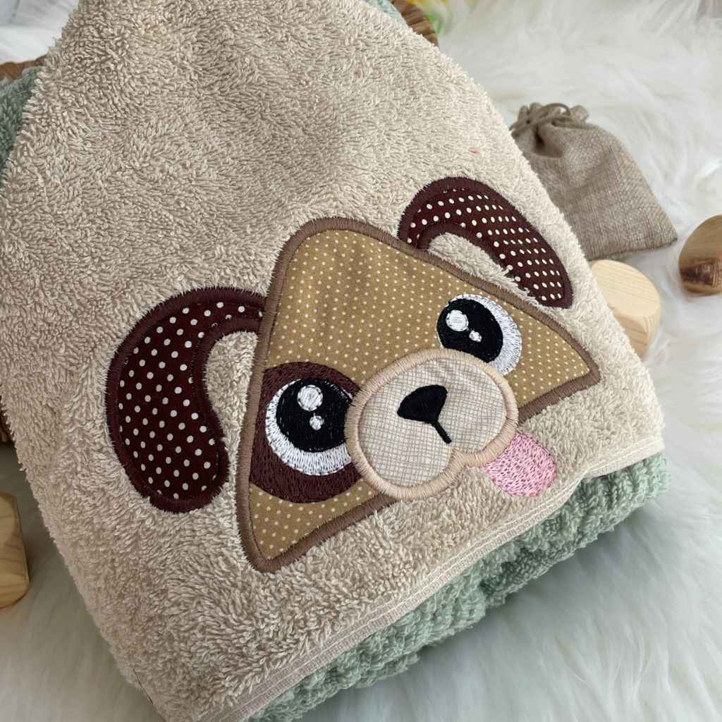 Children's hooded towel with a dog face design on a soft surface