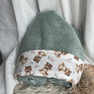 sage green hooded towel sitting on a white background cream fabric trim featuring baby highland calves