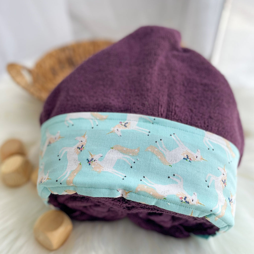 Purple hooded towel folded with unicorn fabric trim