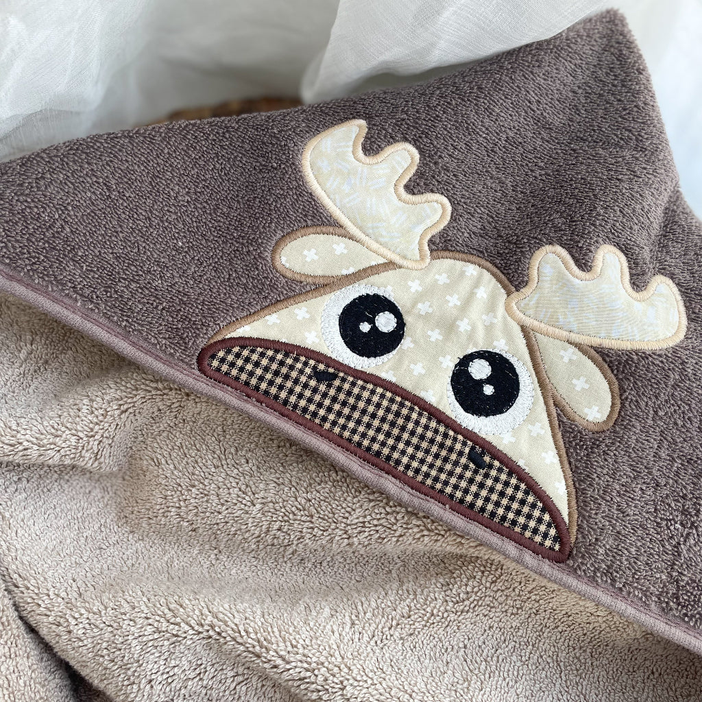 Brown towel with a moose applique on a white background