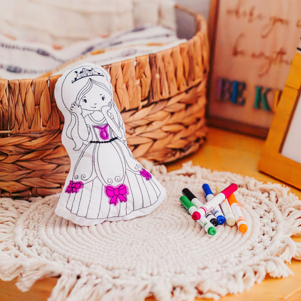 Reusable Princess Coloring Pillow leaning against a wicker basket with markers beside