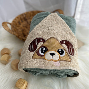 Children's hooded towel with a dog face design on a soft surface.