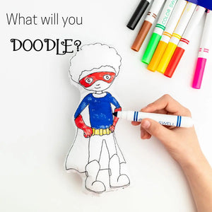 superhero coloring doll with a hand coloring his shirt washable markers laying to the right of the doll