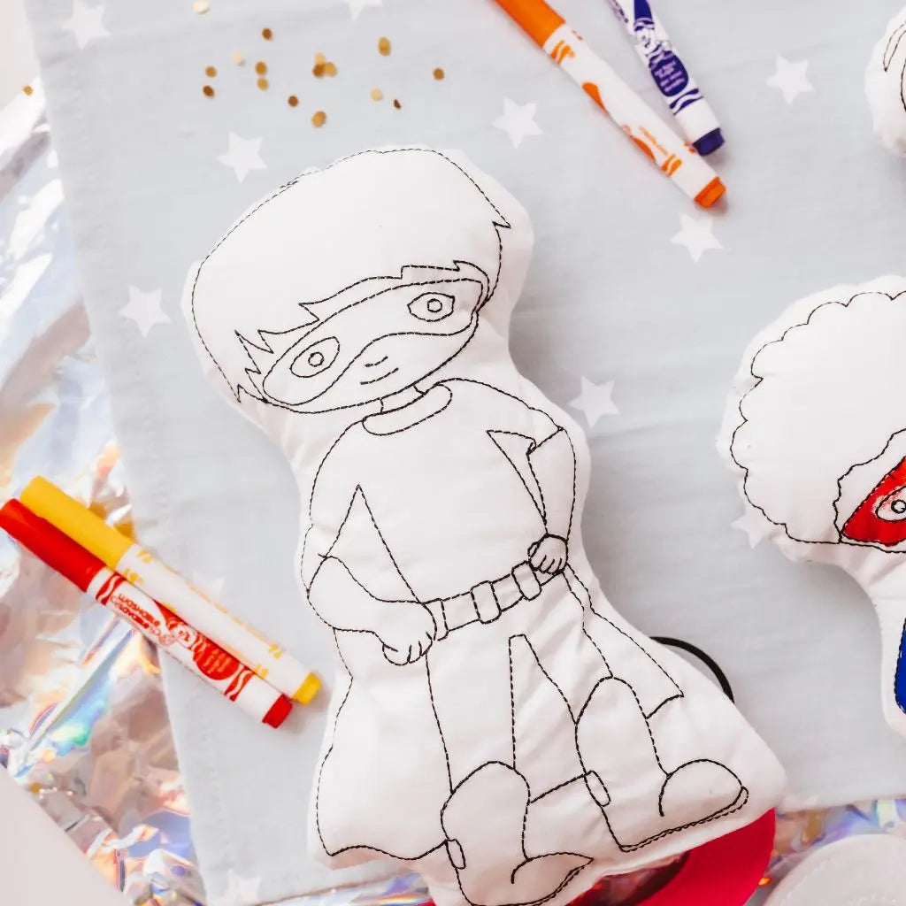 Reusable Superhero Coloring Pillow laying surrounded by washable markers