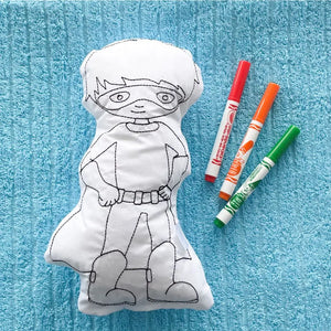 Reusable Superhero Coloring Pillow laying on a blue towel with red orange and green washable markers
