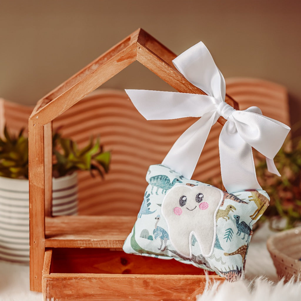 tooth fairy pillow with a grey dinosaur print hanging on a wooden frame