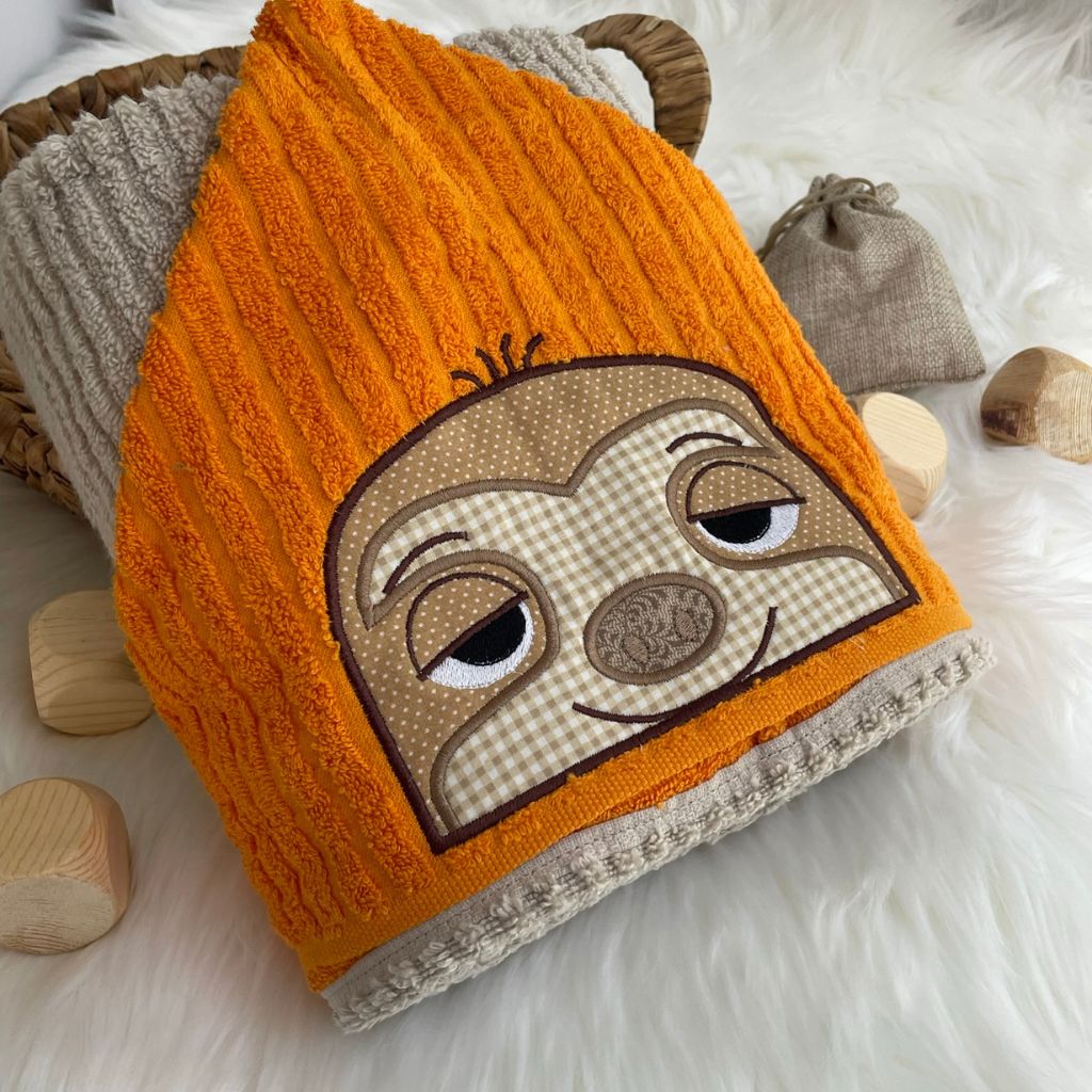 Hooded towel with a cartoon sloth face design on a fluffy white surface