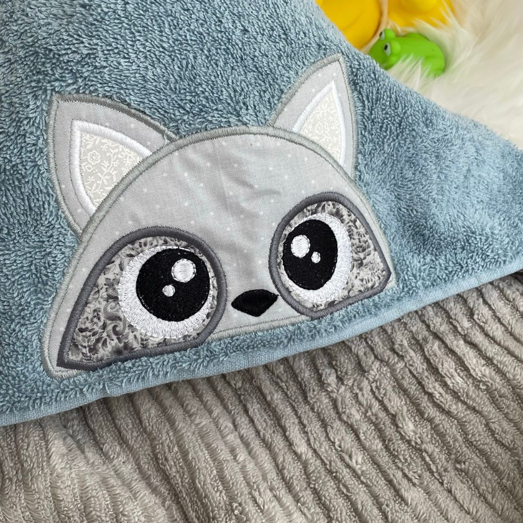Blue towel with a raccoon face design on a hooded towel