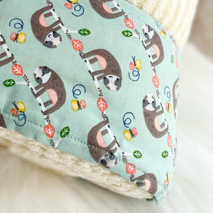 close up of sloths hanging on a mint green fabric