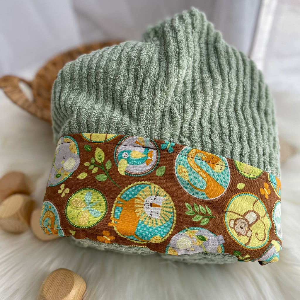 Green towel with a brown trim featuring safari animals