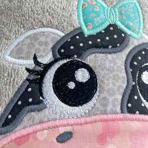 close up Grey towel hood with a black and white cow face with teal bow