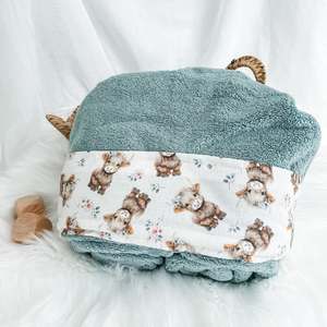 sage green hooded towel sitting on a white background cream fabric trim featuring baby highland calves