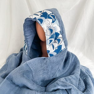 Blue hooded towel on a mannequin with a white background fabric trim featuring toothy shark faces