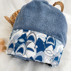 blue hooded towel folded on a white background fabric trim featuring toothy shark faces