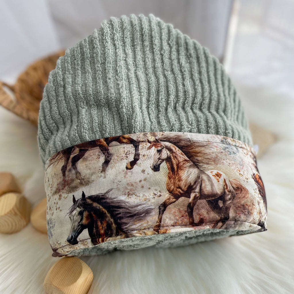 Sage Green hooded towel folded with horse print on a light background